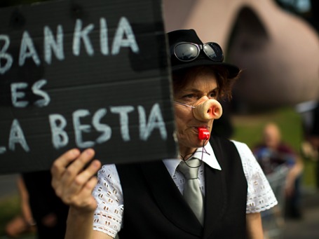 Демонстрант рядом с отделением банка Bankia в Барселоне держит плакат с надписью «Bankia – дикое животное». Фото: AP