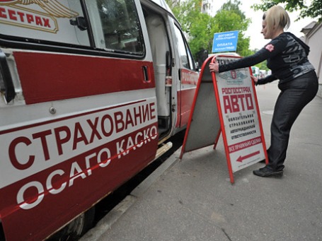 Сотрудница передвижного пункта страхования автомобилей выставляет рекламный штендер перед началом рабочего дня. Фото: РИА Новости