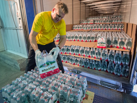 Сотрудник складских служб выгружает партию воды «Боржоми». Фото: РИА Новости