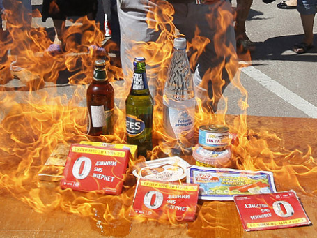 Участники акции протеста против блокирования импорта украинской продукции в Россию сжигают товары российских производителей перед посольством Российской Федерации в Киеве. Фото: Reuters
