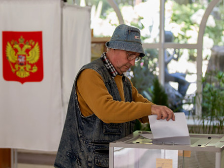 Мужчина опускает избирательный бюллетень в урну для голосования на избирательном участке. Фото: РИА Новости