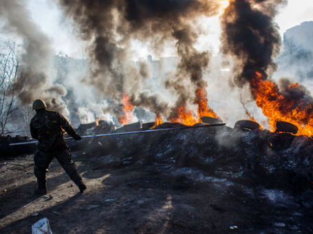 Сторонник радикальной оппозиции подбрасывают автомобильные покрышки в огонь на баррикаде Институтской улице в Киеве. Фото: РИА Новости 