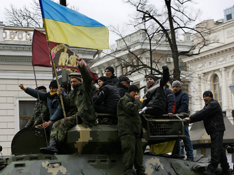 Участники митинга против Виктора Януковича машут украинским флагом на вершине БТР украинской армии у здания парламента в Киеве 27 февраля 2014. Фото: Reuters.