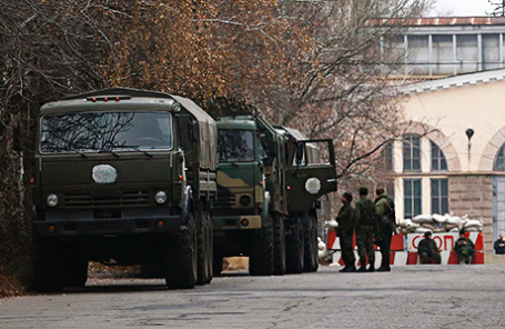 Вооруженные люди рядом с военными грузовиками возле контрольно-пропускного пункта в Донецке.