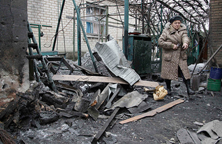 Женщина у развалин дома, пострадавшего в результате обстрела в Донецке.