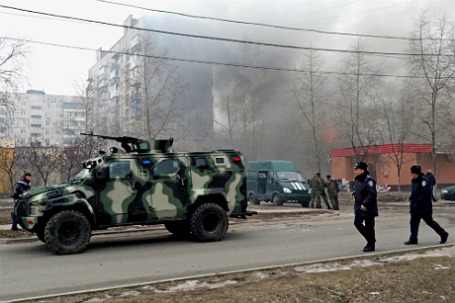 Военный автомобиль у горящего дома на одной из улиц Мариуполя.