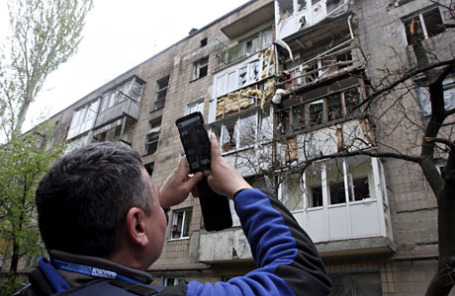 Сотрудник ОБСЕ снимает на камеру последствия обстрелов в Донецке накануне 3 мая 2015.
