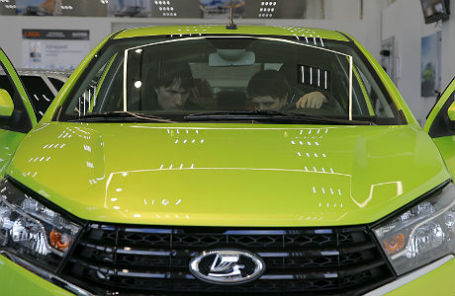 Посетители автосалона осматривают Lada Vesta.