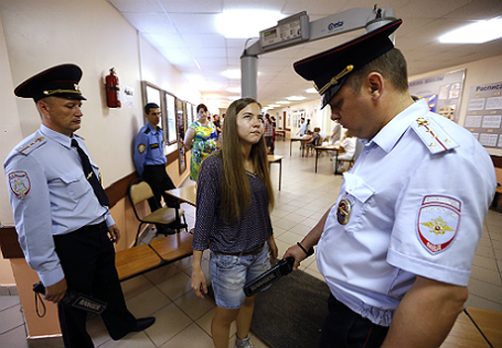 Проверка старшеклассницы на металлоискателе сотрудниками полиции.