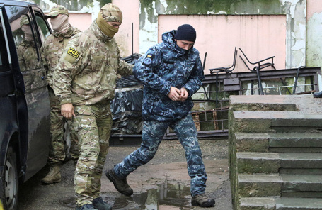 Сотрудник ФСБ России сопровождает задержанного украинского моряка на судебное заседание в Симферополе.