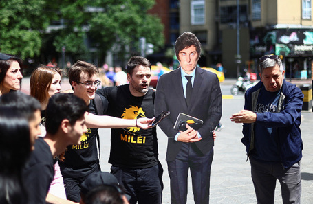 Сторонники кандидата в президенты Аргентины Хавьера Милея стоят рядом с его фигурой во время избирательной кампании.