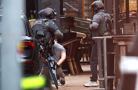 Полицейские задерживают человека возле кафе Petticoat в городе Эде, Нидерланды, где в заложниках удерживаются несколько человек.