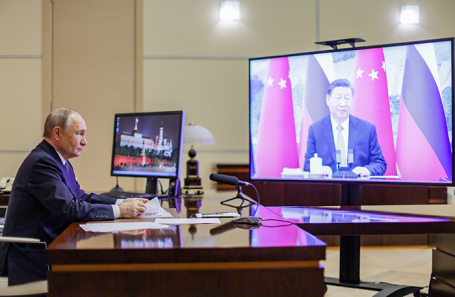 Президент РФ Владимир Путин (слева) и председатель КНР Си Цзиньпин (на экране) во время переговоров в режиме видеоконференции.