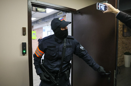 Сотрудник правоохранительных органов выходит из редакции телеграм-канала Baza, где проводились следственные мероприятия.