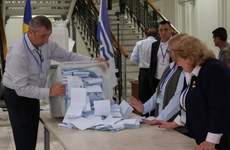 Члены избирательной комиссии опустошают урну для голосования после закрытия избирательных участков на парламентских выборах в Кишиневе 28 сентября 2025 года. 