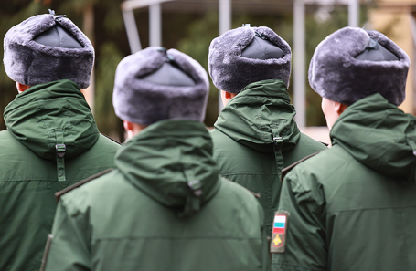 Мужчина держит в руках электронную повестку на фоне военкомата