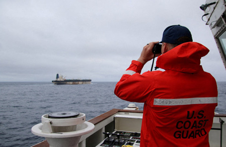 Представитель Береговой охраны США рассматривает в бинокль судно Marinera.