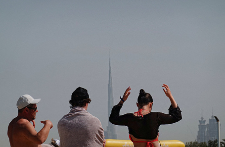 Люди на пляже на фоне небоскреба Бурдж-Халифа после иранской атаки. Дубай, 1 марта 2026 года. 