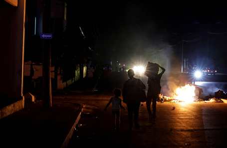 Люди проходят мимо подожженного мусора посреди улицы во время протеста против частых отключений электроэнергии в Гаване.