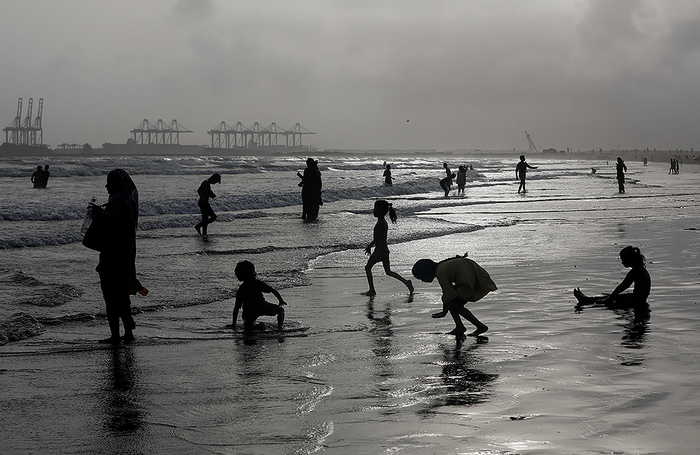 Люди охлаждаются в жаркий день на пляже Клифтон в Карачи, Пакистан.