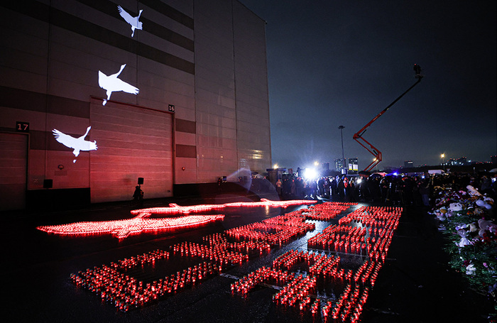 Надпись «Скорбим. 22 марта 2024», выложенная из свечей, и иллюминация в виде белых журавлей на фасаде здания Crocus City Hall.