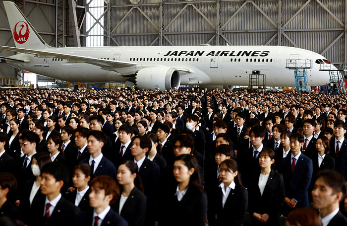 Недавно принятые на работу сотрудники Japan Airlines присутствуют на церемонии вступления в должность в ангаре международного аэропорта «Ханэда» в Токио.