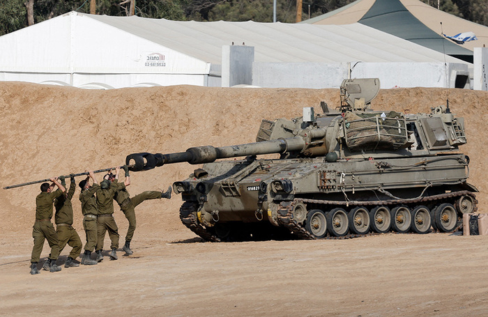 Израильские солдаты чистят ствол мобильной артиллерийской установки недалеко от границы Израиля и сектора Газа.