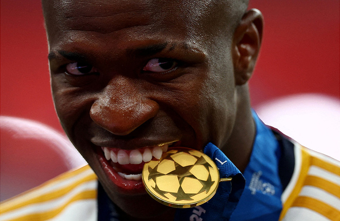 Нападающий мадридского «Реала» и сборной Бразилии Винисиус Жуниор позирует с медалью во рту. Мадридский «Реал» в 15-й раз в своей истории победил в Лиге чемпионов по футболу, клуб обыграл дортмундскую «Боруссию» со счетом 2:0.