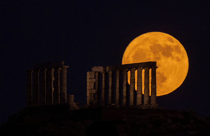 Клубничная луна восходит за храмом Посейдона на мысе Сунион, Греция.