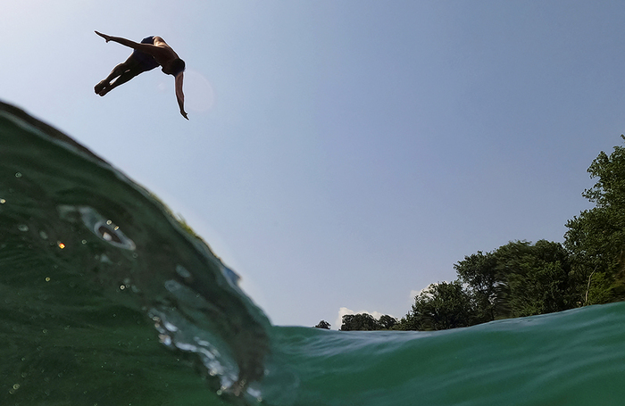Мужчина прыгает в реку Дринос во время жары недалеко от Тепелены, Албания.