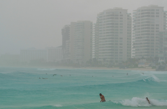 Пляж в канкуне. Туристы купаются в океане, в то время как тропический шторм «Элен» приближается к полуострову Юкатан, Мексика.