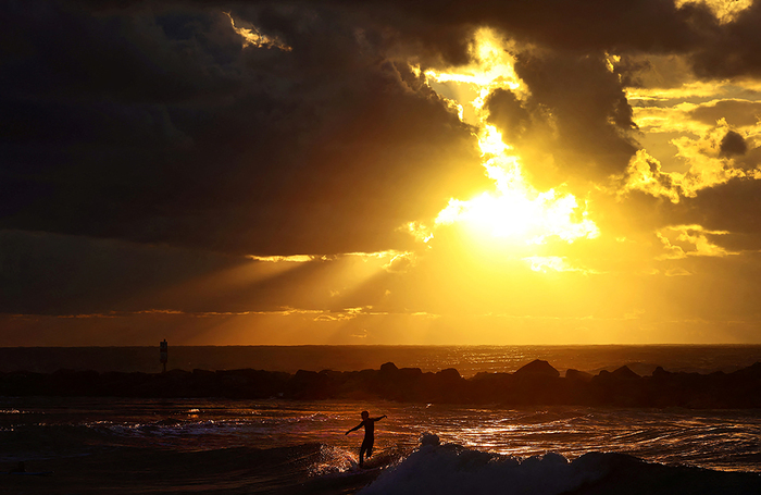 Серфер наслаждается последним закатом года в Тель-Авиве, Израиль.