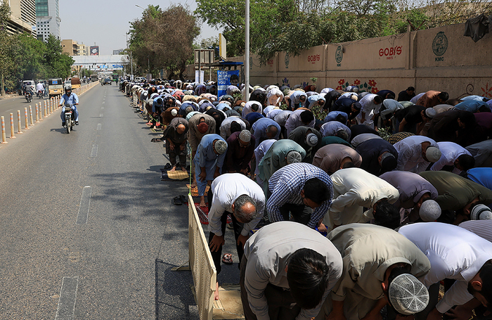Верующие посещают пятничную молитву во время священного для мусульман месяца Рамадан возле мечети вдоль дороги в Карачи, Пакистан.