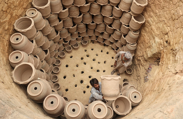 Рабочие расставляют глиняные горшки в печи, чтобы обжечь их перед тем, как выставить на продажу на фабрике в Пешаваре, Пакистан.