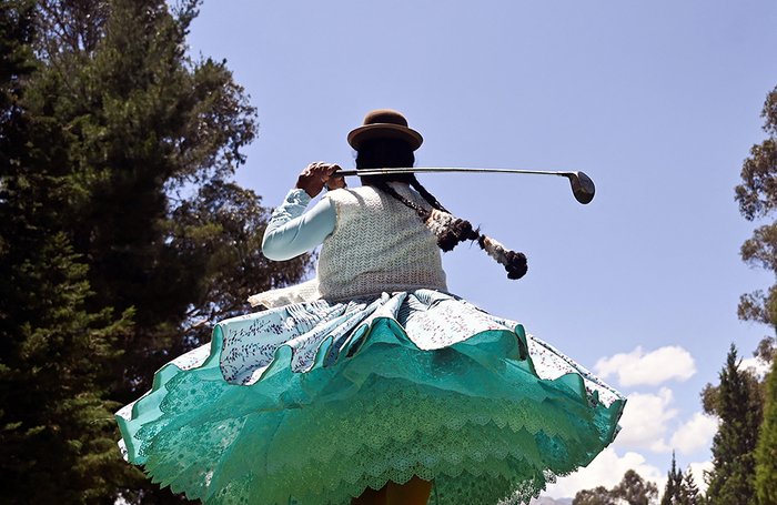 Гольфистка из племени чолита в традиционных юбках поллера играет в гольф-клубе в Ла-Пасе, Боливия.