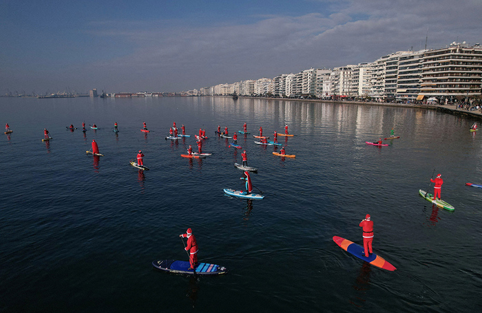 Рождественский заплыв Санта-Клаусов на сапбордах в Салониках, Греция.