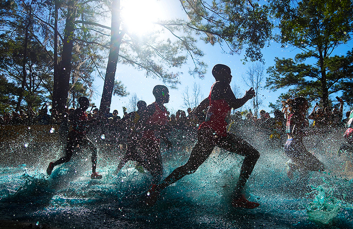 Бегуньи в забеге среди девушек до 20 лет пробегают через озеро Саншайн Сплэш во время чемпионата мира по кроссу в Таллахасси.