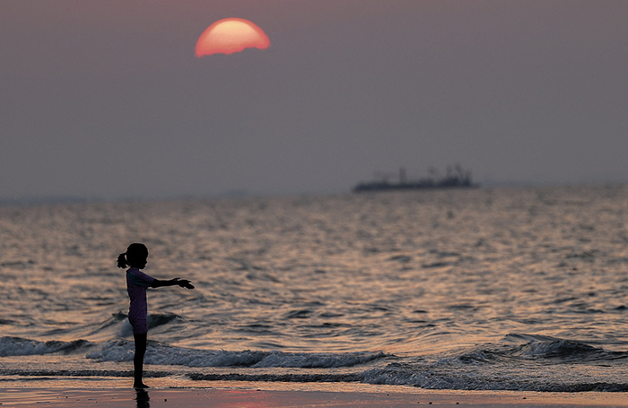 Ребенок играет на пляже Курум на закате. Маскат, Оман.