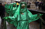 Участники группы экологических активистов из Extinction Rebellion в зеленых мантиях принимают участие в акции «The Big One» в Лондоне, Великобритания.