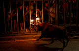 Прохожие смотрят на быка с пылающими рогами во время фестиваля «бу эмболат», который был запрещен в Валенсии в 2016 году, но восстановлен новым региональным правительством, в Карпесе, северная Валенсия, Испания.