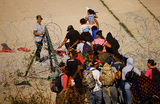 Мигранты прорываются за колючую проволоку на границе Мексики и США в районе Сьюдад-Хуареса. 