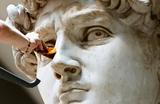 Реставратор очищает от пыли и мусора статую Давида Микеланджело в Галерее Академии во Флоренции, Италия.