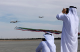 Посетители Международного авиасалона Dubai Airshow 2023. В небе  самолеты Airbus A380 (слева) и Boeing 777 авиакомпании Emirates Airlines, и пилотажная группа  Al Fursan ВВС ОАЭ. 