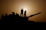 Израильские солдаты стоят на танке во время заката недалеко от границы Израиля с сектором Газа на юге Израиля.