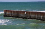 Мужчина пытается пересечь границу между Мексикой и Соединенными Штатами в Плайяс-де-Тихуана, Мексика.