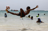 Мальчик играет в футбол в водах Индийского океана на пляже Лидо в Могадишо. Сомали.