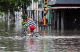 Мужчина пытается проехать на велосипеде по улице, затопленной проливными дождями, в Авельянеде на окраине Буэнос-Айреса, Аргентина.