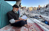 Палестинец Исмаил Аль-Хлут читает Коран, сидя на развалинах своего дома, во время священного месяца Рамадан в Бейт на севере сектора Газа.