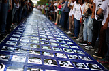 Демонстранты, помятуя 48-ю годовщину памяти жертв военного переворота в Аргентине (1976 год) , стоят рядом с баннером, на котором видны фотографии пропавших в то время без вести людей. Буэнос-Айрес, Аргентина.