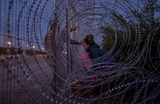 Мигрантка из Венесуэлы со своей трехлетней дочкой пытаются прорваться через пограничный забор с колючей проволокой у реки Рио-Гранде в Эль-Пасо, штат Техас, США.